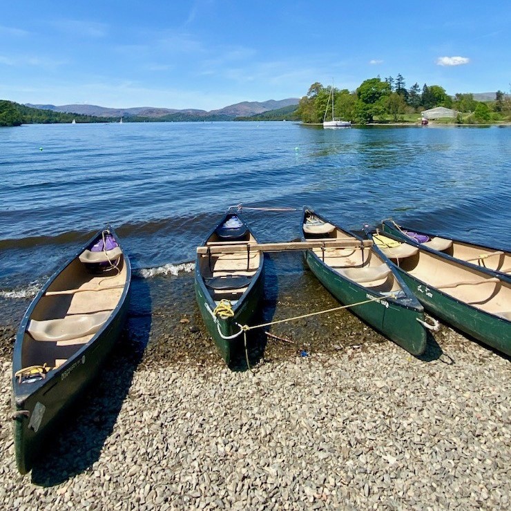 Row boats on a pebble beach on the shore of Lake Windermere